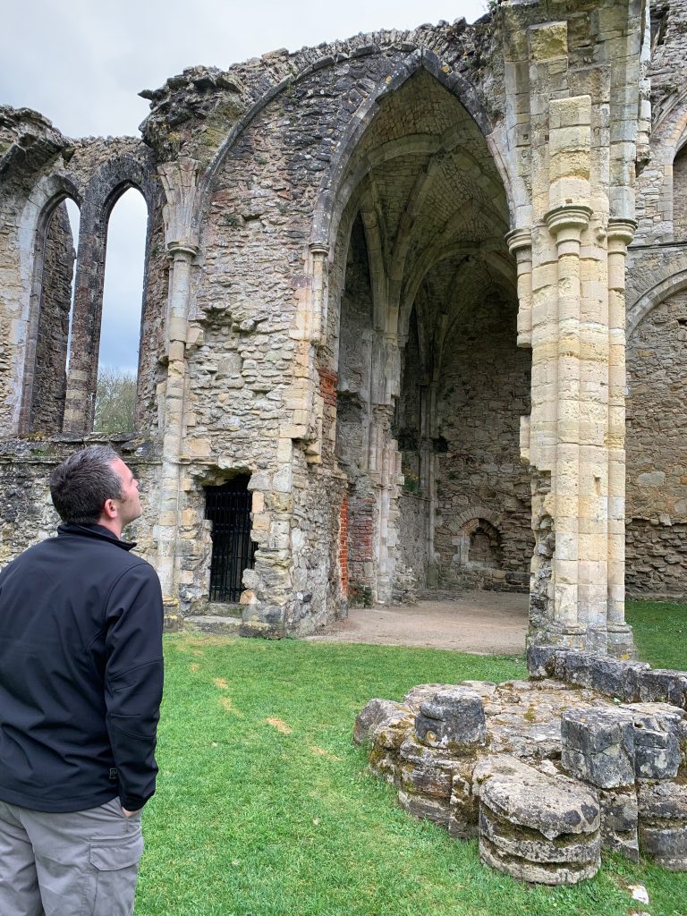 Man standing amongst the ruins of Netley Abbey, marvelling at them