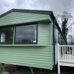 A green static caravan with front decking