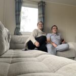 A man and a woman sit comfortably on a sofa in a static caravan