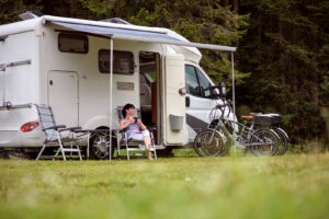 Woman is sitting with a mug of coffee next to a Motorhome