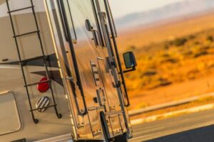 a Motorhome is driving along an open road with the desert in the background