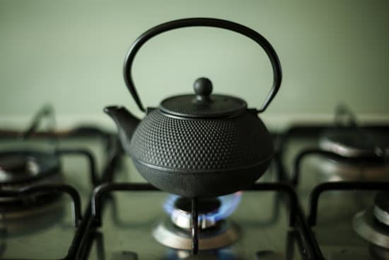 A black kettle is atop a lit gas stove