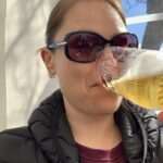 A lady sips a beer in a beer garden on a sunny day