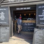 A man stands at the counter of a harbour front smokehouse called the Sole Bay Fish Company 