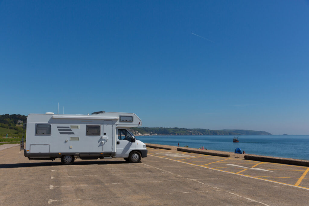 Motorhome is parked up in a carpark at the beach, facing out to the water