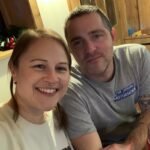 A man and woman pose together in a cosy pub setting