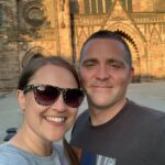 A man and woman pose tighter in front of a Church in Hereford