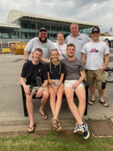 A group of people are sitting on a bench and posing for the camera, all smiling