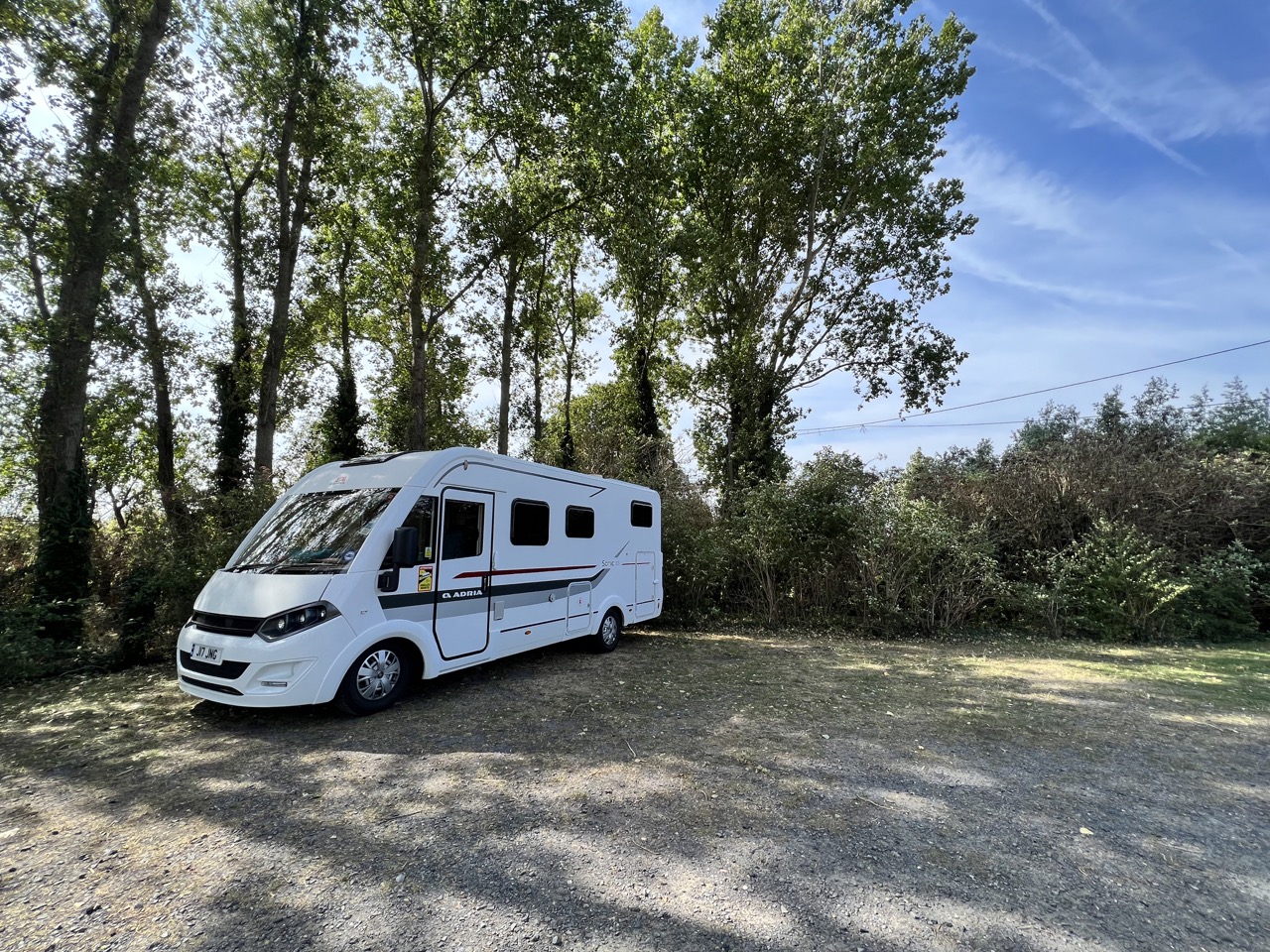 The image shows an a class motorhome parked up in a beautiful wooded area