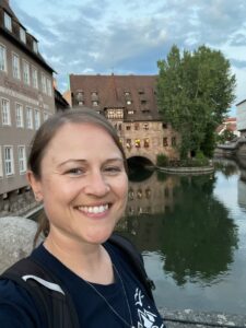 A lady smiles for a selfie, taken from the bridge in nuremberg city, overlooking the river pegnitz