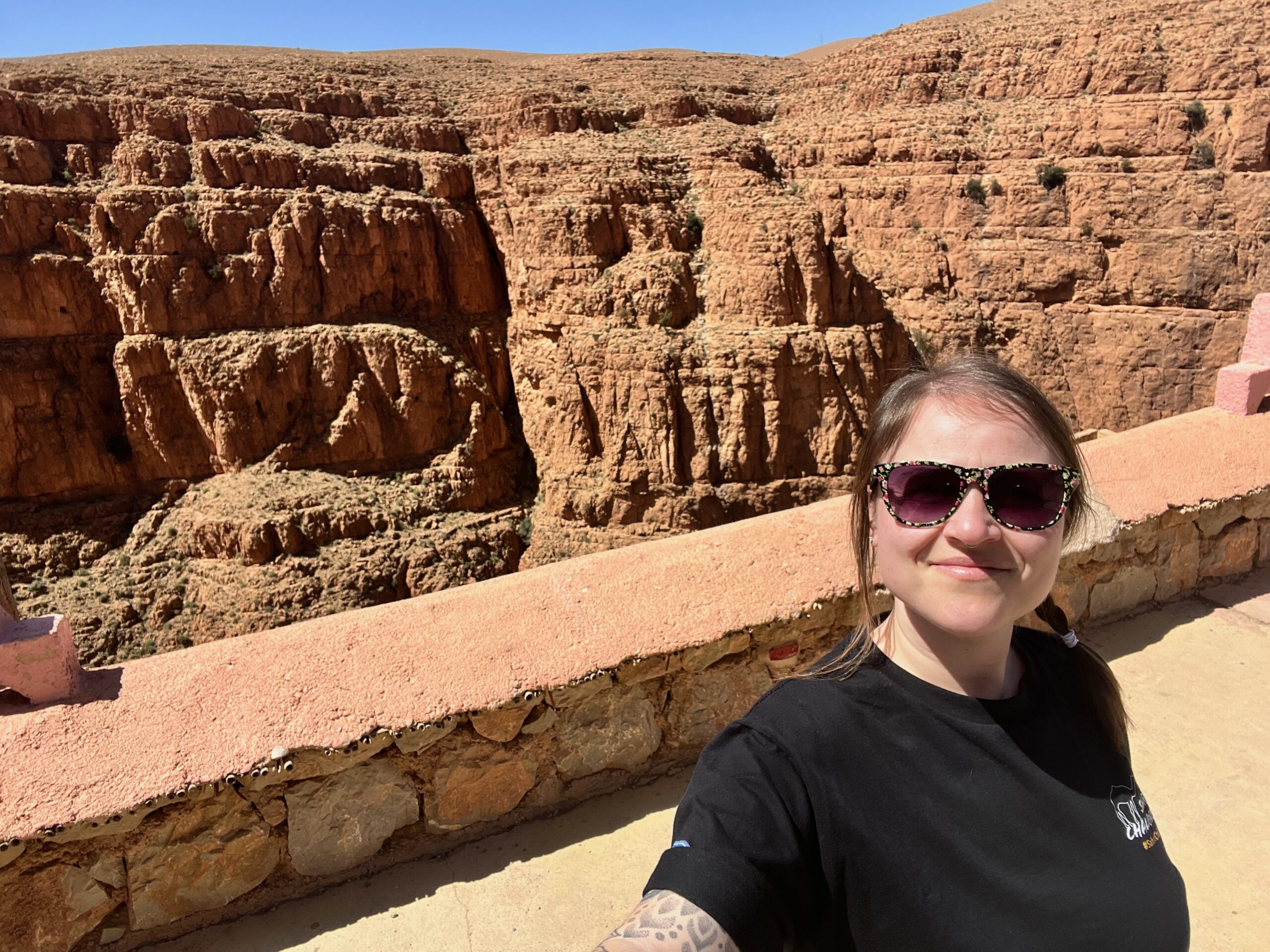 A lady stands smiling from the viewpoint at the top of the Dades Gorge