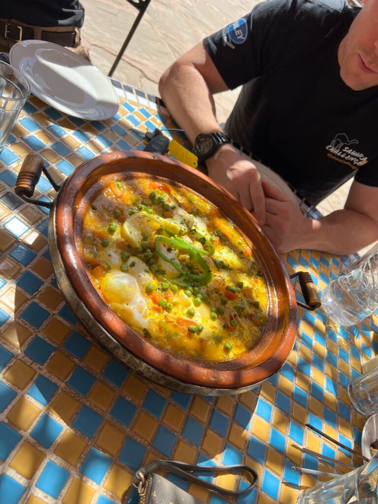 A baked egg tagine is on a table, on the outside terrace of a cafe
