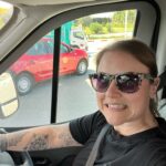 A lady sits in the drivers seat of a motorhome, pulling a nervous face 
